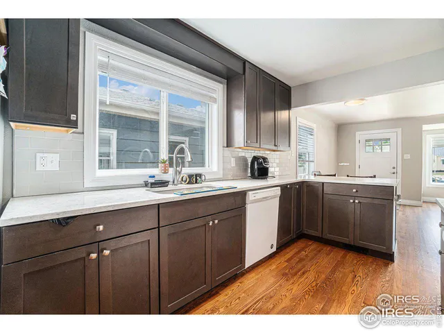a kitchen with stainless steel appliances granite countertop a sink cabinets and wooden floor