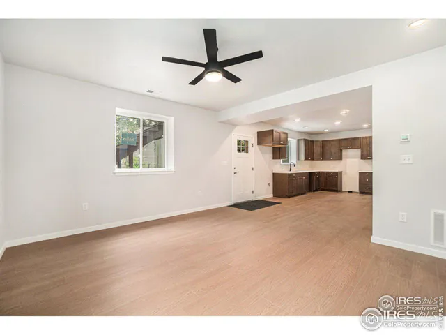 a view of a livingroom with a ceiling fan & windows