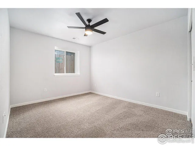 an empty room with a ceiling fan and window