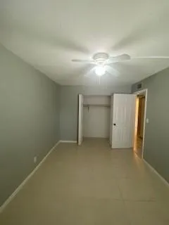 an empty room with closet and a ceiling fan