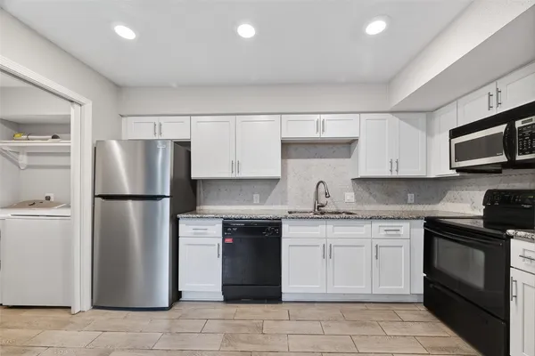 a kitchen with stainless steel appliances granite countertop a refrigerator stove a sink and a microwave