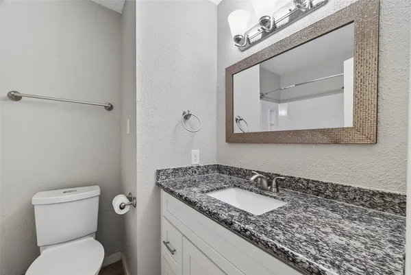a bathroom with a granite countertop toilet sink and mirror