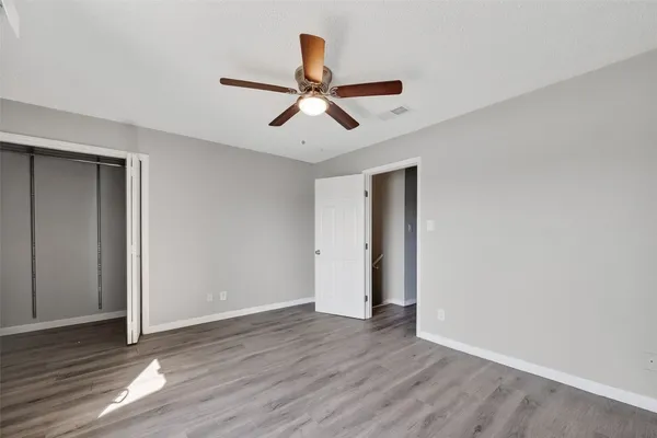 a view of empty room with wooden floor and ceiling fan