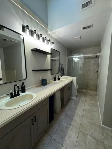 a bathroom with a double vanity sink a mirror and a shower