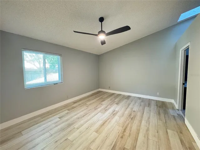 a view of empty room with wooden floor and fan