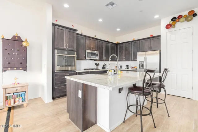 a kitchen with stainless steel appliances kitchen island granite countertop a refrigerator and a stove top oven