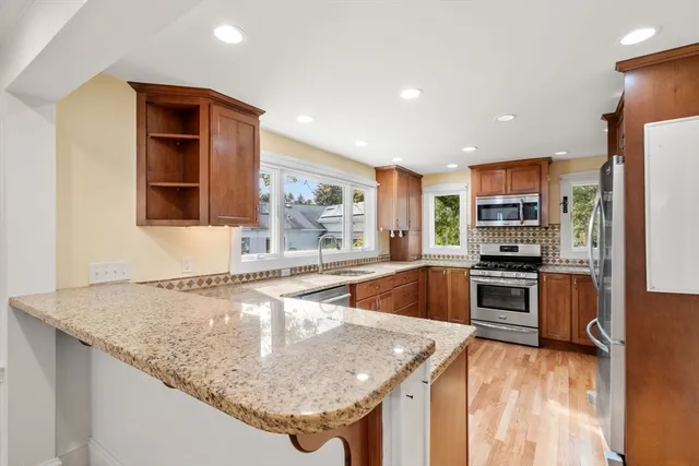 a kitchen with stainless steel appliances granite countertop a sink a stove and a refrigerator
