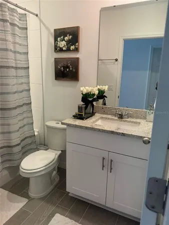 a bathroom with a granite countertop toilet sink and mirror