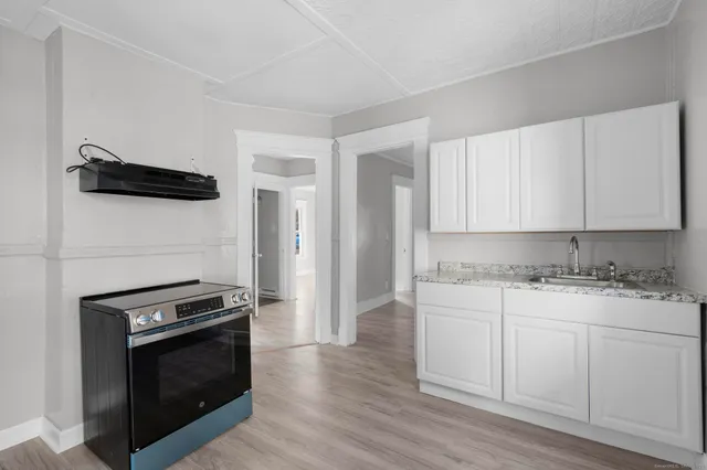 a kitchen with granite countertop white cabinets and stainless steel appliances