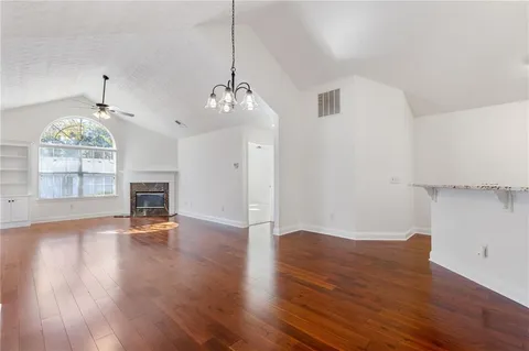 a view of a room with wooden floor fireplace and window