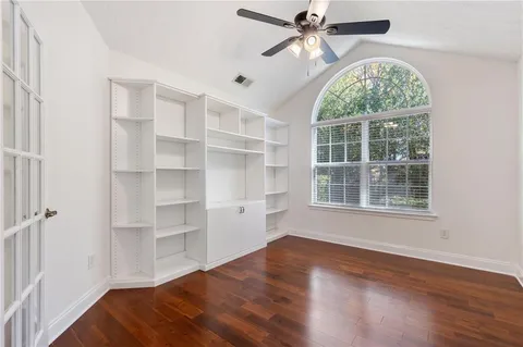 a view of an empty room with a window and wooden floor