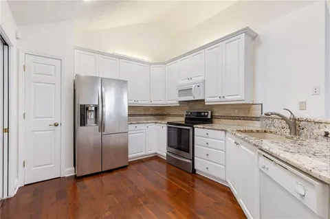 a kitchen with stainless steel appliances granite countertop a refrigerator sink and white cabinets