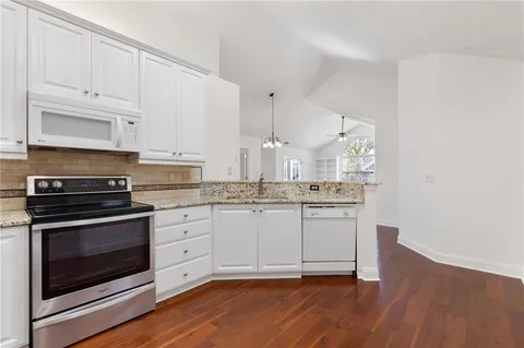 a kitchen with stainless steel appliances granite countertop a stove and white cabinets