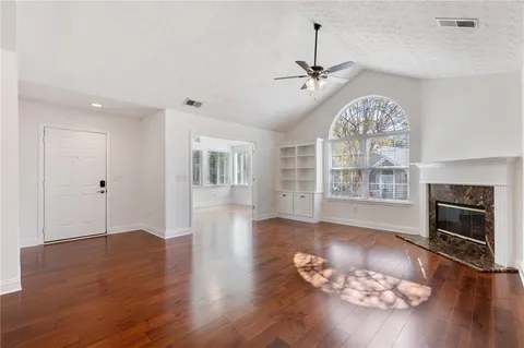 an empty room with wooden floor fireplace and windows