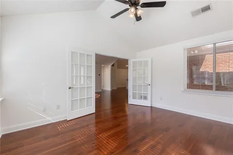 an empty room with wooden floor closet and windows