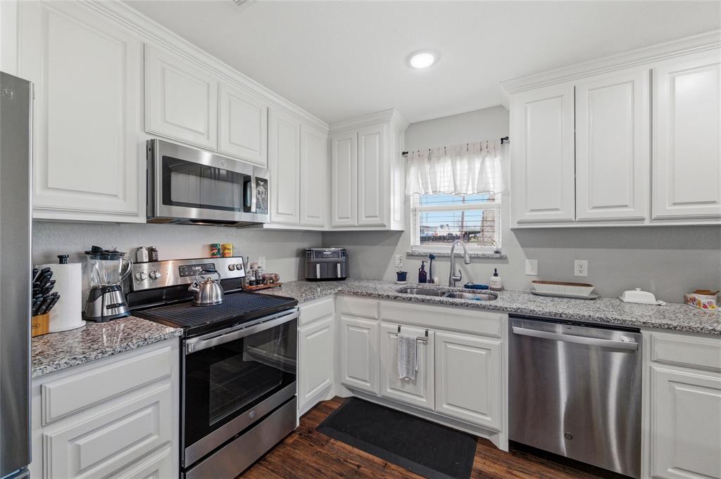 300 West Main Street Itasca, TX 76055 - Photo 6 of 31 a kitchen with granite countertop white cabinets sink and stainless steel appliances