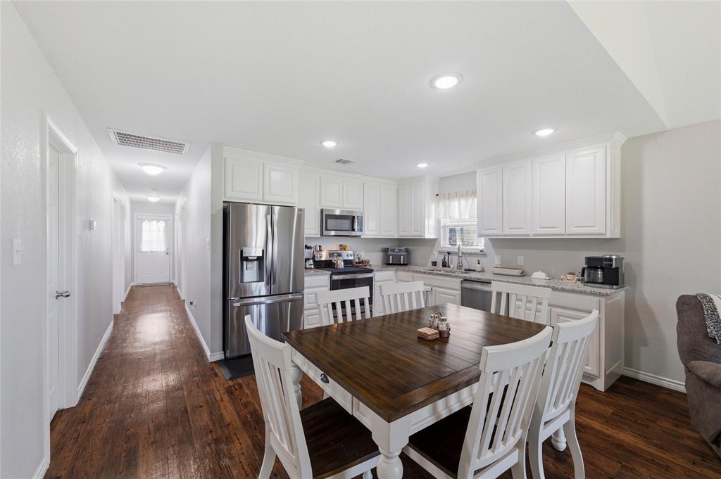 300 West Main Street Itasca, TX 76055 - Photo 7 of 31 a kitchen with stainless steel appliances granite countertop a dining table chairs refrigerator and microwave
