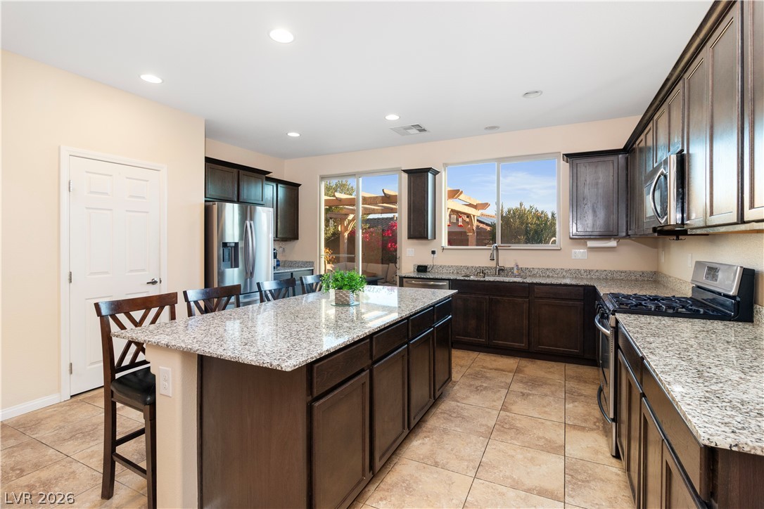 2079 Port Royal Drive Laughlin, NV 89029 - Photo 14 of 86 Kitchen with a kitchen bar, stainless steel appliances, dark brown cabinets, light stone counters, and a kitchen island