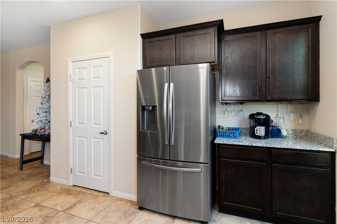2079 Port Royal Drive Laughlin, NV 89029 - Photo 15 of 86 Kitchen featuring stainless steel fridge with ice dispenser, dark brown cabinetry, light stone countertops, and light tile patterned flooring