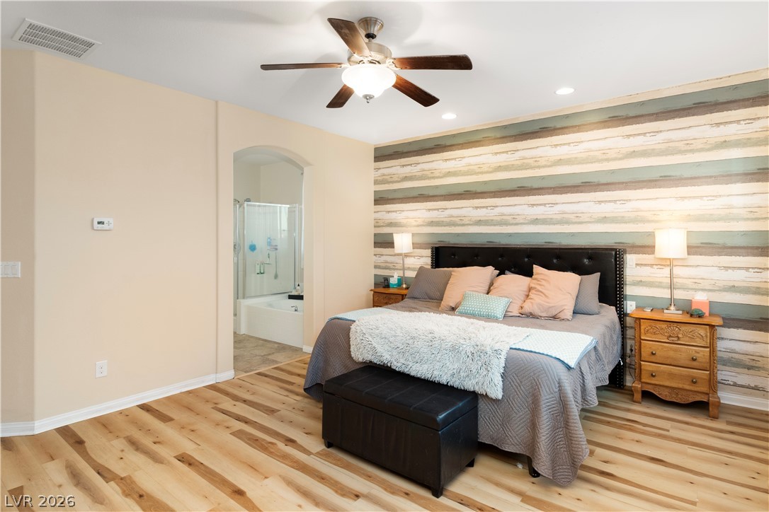 2079 Port Royal Drive Laughlin, NV 89029 - Photo 25 of 86 Primary Bedroom with ensuite bath, wood finished floors, an accent wall, arched walkways, and wood walls