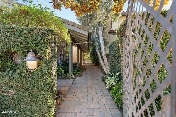 a view of a pathway with flower plants and wooden fence