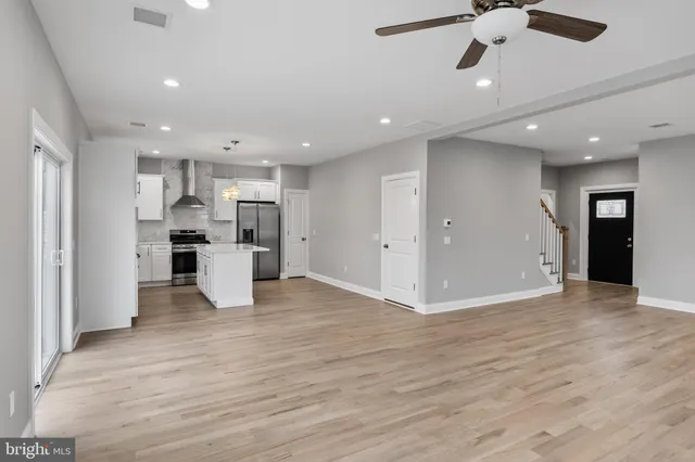 a kitchen with stainless steel appliances kitchen island granite countertop a stove top oven a refrigerator and white cabinets with wooden floor