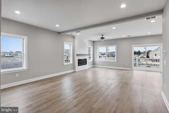 an empty room with wooden floor fireplace and windows