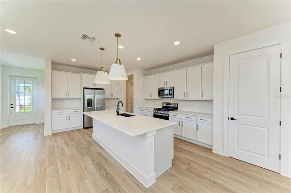 a large kitchen with cabinets wooden floor and stainless steel appliances