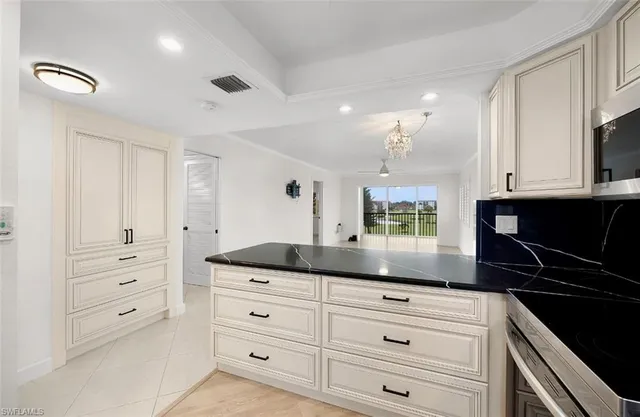 a kitchen with granite countertop white cabinets and black appliances