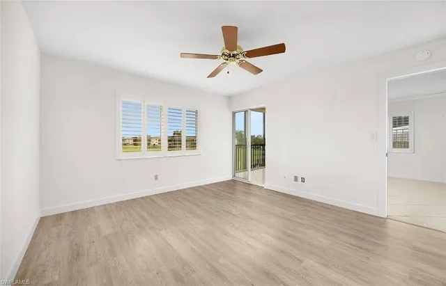 an empty room with wooden floor ceiling fan and windows