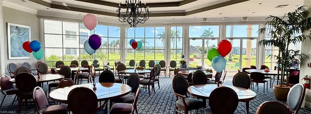 a view of a dining room with furniture a chandelier and large window