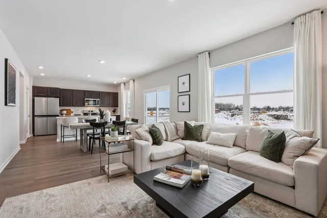 a living room with furniture kitchen view and a large window