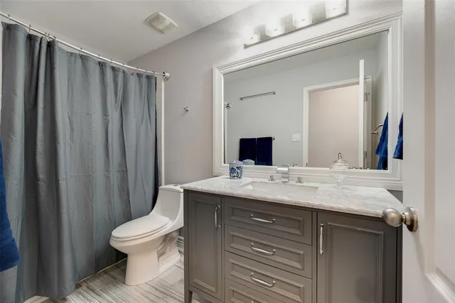 a bathroom with a granite countertop sink toilet and mirror