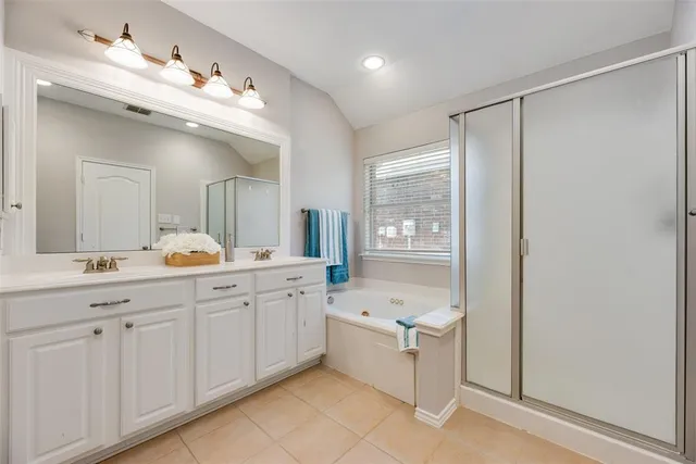 a spacious bathroom with a double vanity sink mirror and bathtub