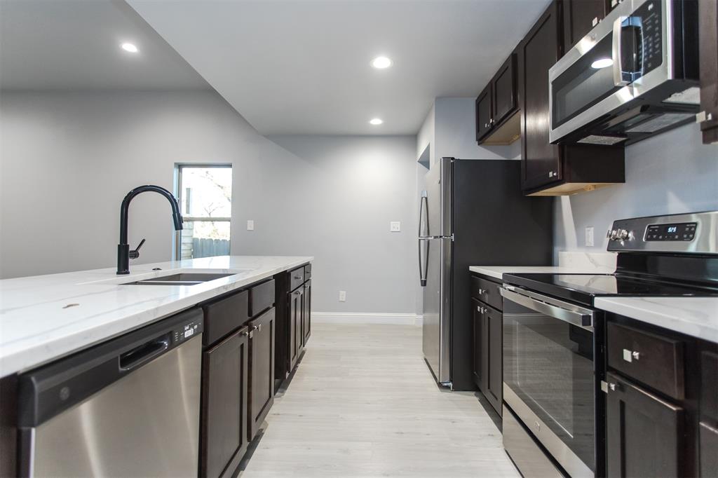 415 West Elm Street, Unit 415 Denison, TX 75020 - Photo 2 of 17 a kitchen with stainless steel appliances granite countertop a sink a stove and a refrigerator