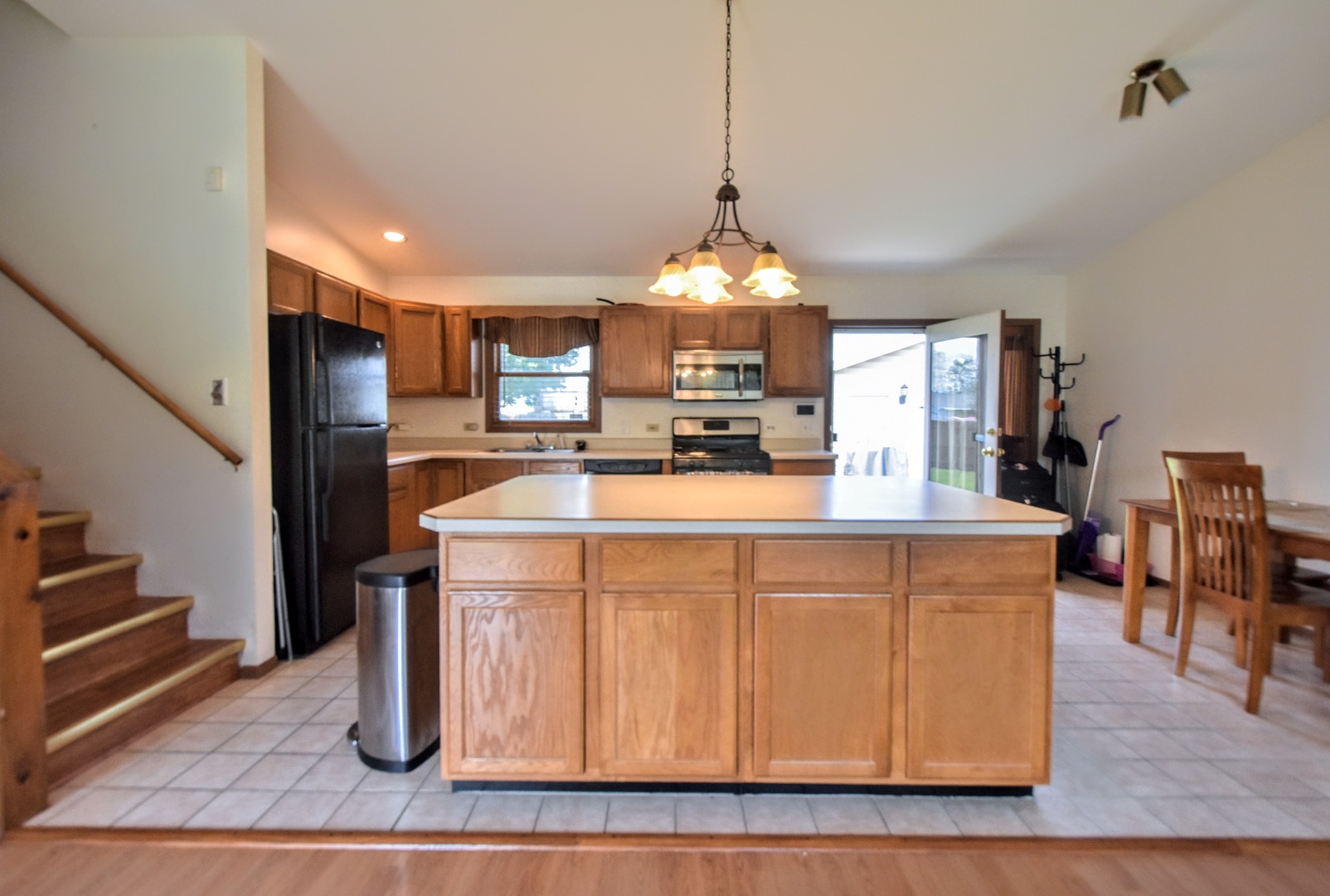 4002 Ridge Road Zion, IL 60099 - Photo 10 of 26 a kitchen with stainless steel appliances granite countertop a refrigerator a sink dishwasher a stove and a dining table with wooden floor