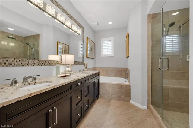 a spacious bathroom with a granite countertop double vanity sink a mirror and a shower