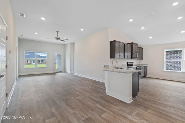 a view of kitchen with stainless steel appliances granite countertop a stove top oven a sink and a refrigerator
