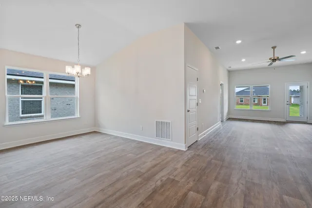 a view of an empty room with window and wooden floor