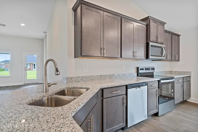a kitchen with stainless steel appliances granite countertop a sink and cabinets with wooden floor
