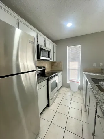 a kitchen with granite countertop a refrigerator and a sink