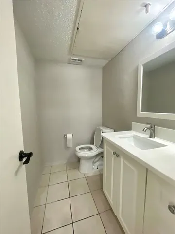 a bathroom with a granite countertop toilet a sink a mirror and shower