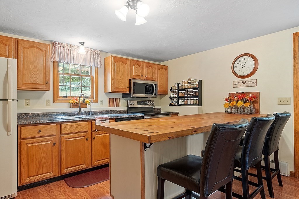 252 Great Road Shirley, MA 01464 - Photo 28 of 42 a dining hall with stainless steel appliances granite countertop a stove a sink dishwasher a dining table and chairs with wooden floor