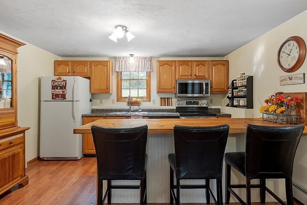 252 Great Road Shirley, MA 01464 - Photo 30 of 42 a kitchen with stainless steel appliances granite countertop a stove a sink dishwasher and a refrigerator with wooden floor