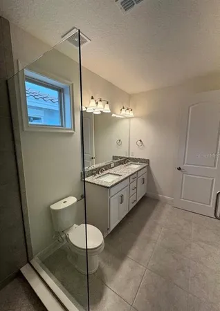a spacious bathroom with a granite countertop sink a toilet a mirror and shower