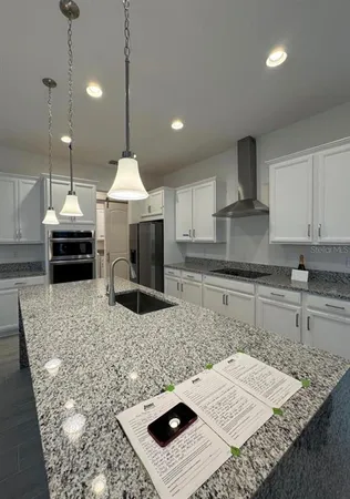 a kitchen with kitchen island granite countertop a sink a counter top space appliances and cabinets