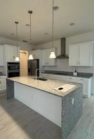 a kitchen with stainless steel appliances granite countertop a sink a stove a oven a kitchen island with cabinets and wooden floor