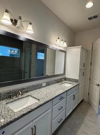 a bathroom with a granite countertop double vanity sink and a mirror