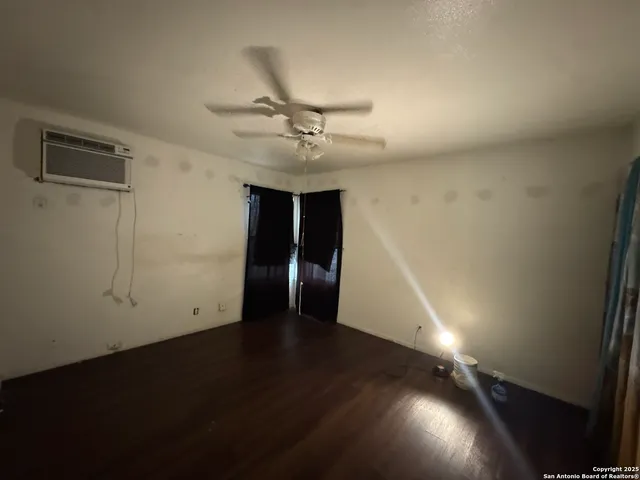 an empty room with wooden floor fan and windows
