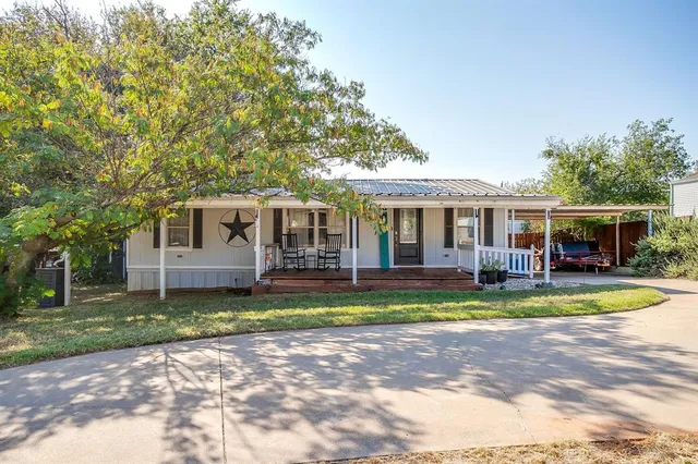 a view of a house with a yard and large tree